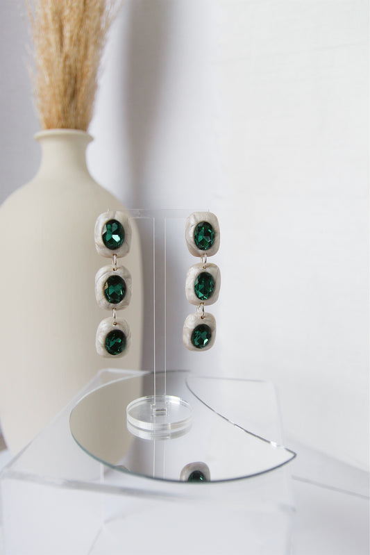 White circular earrings with emerald green rhinestones.